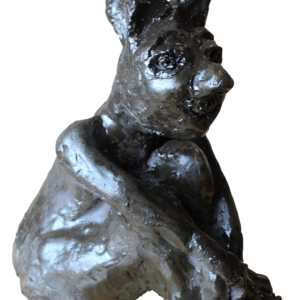 Sculpture d'argile peinte à l'acrylique représentant un homme lapin complètement noir, au regard triste et inquiet, assis avec les bras timidement croisés sur ses genoux pliés devant lui.